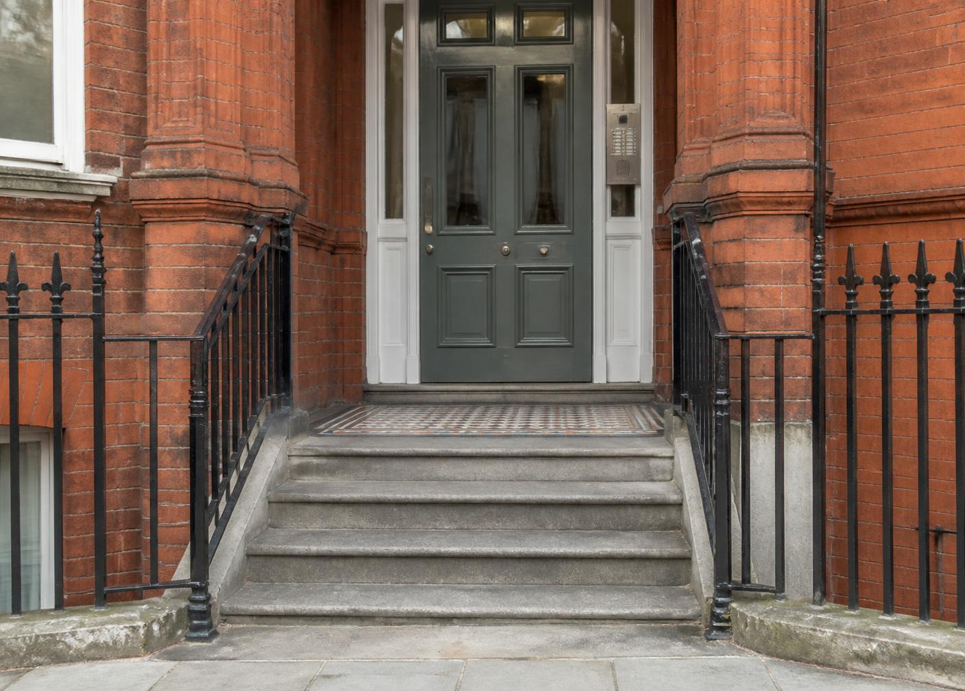 Communal entrance of a red-brick London mansion block with stone steps and railings