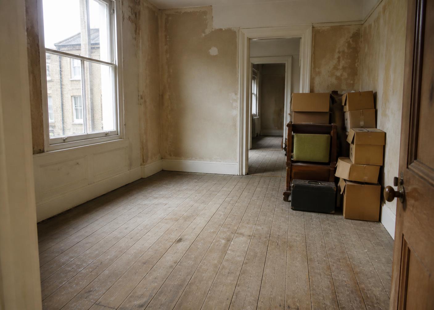 Empty London flat with bare floorboards and remaining boxes awaiting clearance